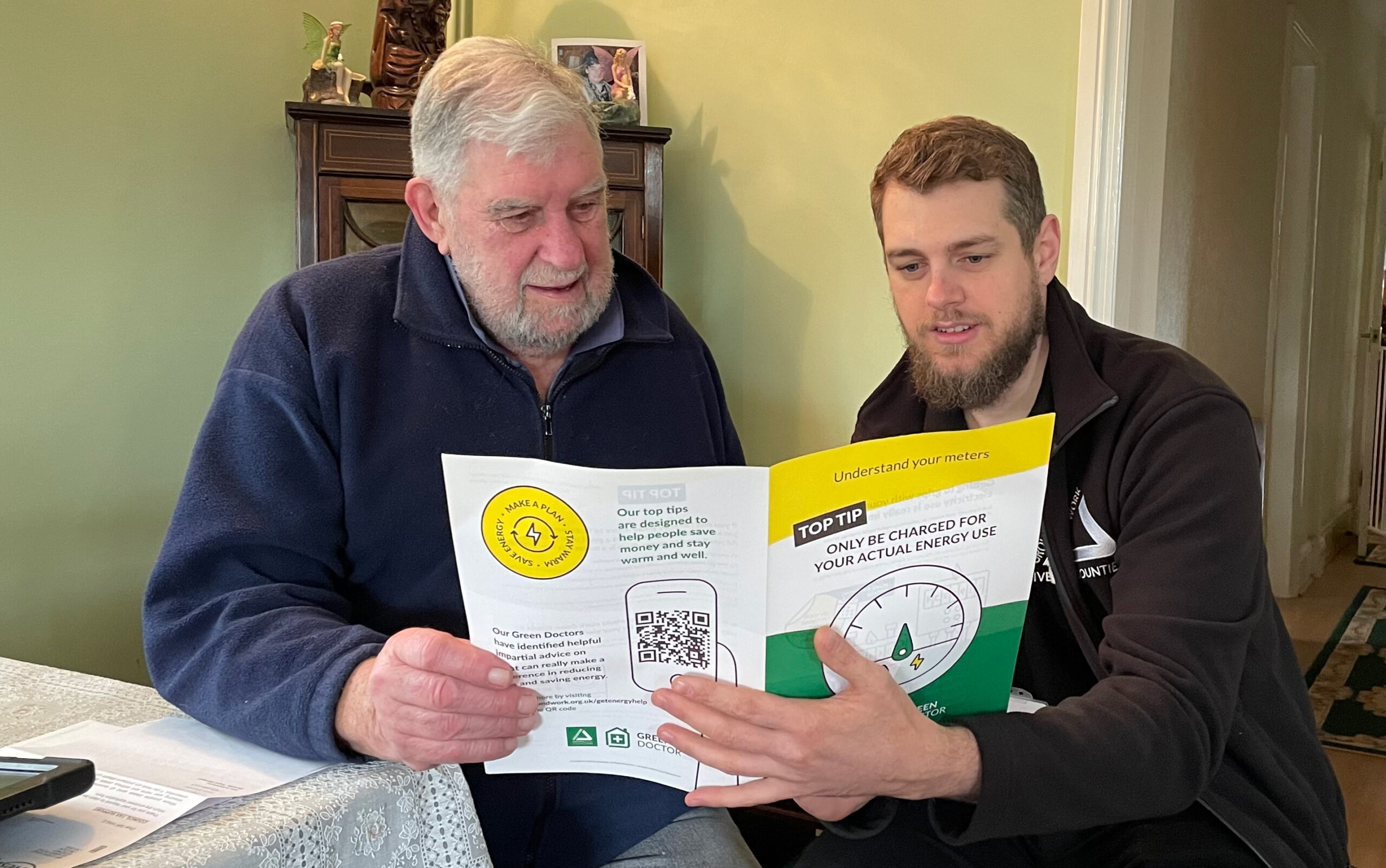 Two men looking at yellow and green brochure about saving energy.